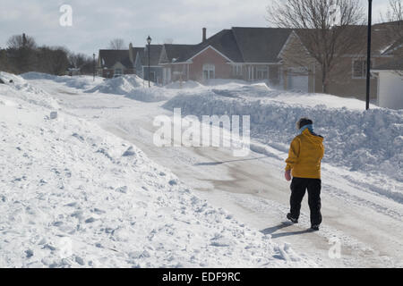 Einsame Fußgänger zu Fuß durch Vorstadt während der Wind den Schnee wild um sie herum peitscht. Stockfoto