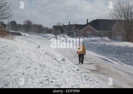 Einsame Fußgänger zu Fuß durch Vorstadt während der Wind den Schnee wild um sie herum peitscht. Stockfoto