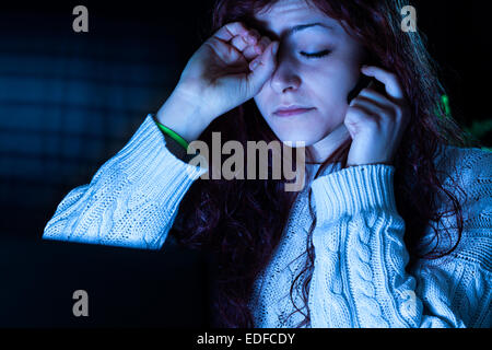 Müde Frau arbeitet in der Nacht auf einem Computer mit Kopfhörer Stockfoto