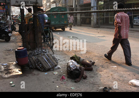 Straßenszene in Old Delhi, Indien - Mann, der auf dem Boden liegt und Leute vorbeilaufen Stockfoto