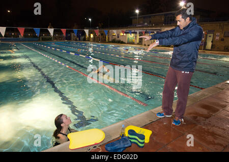 Am Abend Schwimmunterricht gegeben von Salim Ahmed im Freien bei Hampton Pool, Middlesex, England, UK Stockfoto