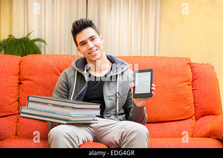 Junger Mann zeigt Unterschied zwischen Ebook-Reader und schwere Bücher Stockfoto