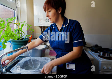 NHS Gemeinschaft Krankenschwester eine Plastikschüssel mit Wasser zu füllen, während der Arbeit in der Heimat eines Patienten in Derbyshire England UK Stockfoto