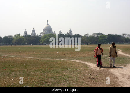 Männer, die zu Fuß auf dem Maidan, Kolkata (Kalkutta), mit Victoria Memorial dahinter Stockfoto