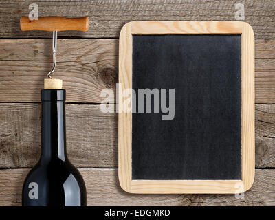 Flasche Wein und leere Tafel auf hölzernen Hintergrund Stockfoto