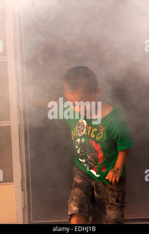 Ein kleiner Junge verlassen ein Überleben lebendig Gebäude mit Rauch gefüllt Stockfoto