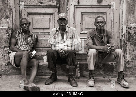 Archiv der Cuba Street.  Drei kubanische Männer sitzen auf Portal in Alt-Havanna. Stockfoto