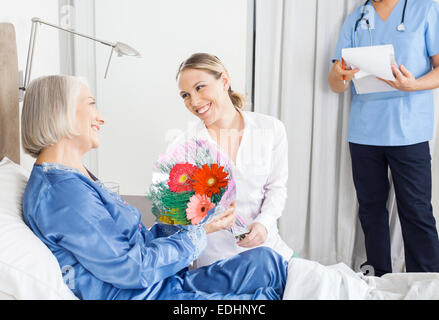 Tochter, die kranke Mutter im Pflegeheim Bouquet verleihen Stockfoto