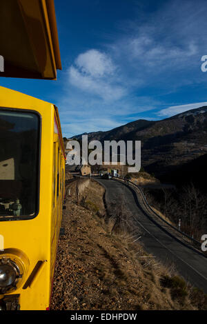 Der Train Jaune, gelber Zug, Canari oder Ligne de Cerdagne, kreuzt die Route nationale 116-Straße. Der Zug verhandelt eine 63km lo Stockfoto