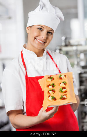 Glückliche Frau Koch Holding gefüllte Ravioli Pasta Blatt In Küche Stockfoto