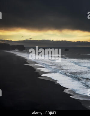 Wellen am Ufer mit Dryholaey im Hintergrund, Island. Dyrhólaey übersetzt bedeutet "Der Tür Loch Island" Stockfoto