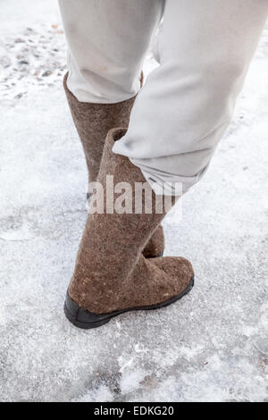 Männliche Füße mit traditionellen russischen fühlte Stiefel Winter mit Schnee und Eis unterwegs stehen Stockfoto