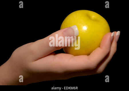 Ein einzelnes gelber Apfel in eine Frau, die gut gepflegten hand Stockfoto