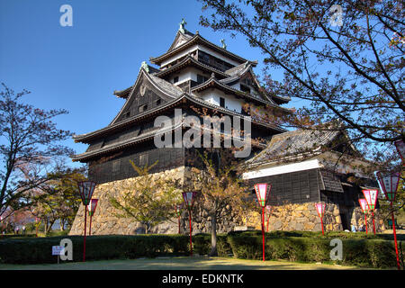 Matsue Castle in Japan. Tagesansicht des Borogata-Stils halten, Tenshu mit frühlingshaften Kirschblütenlaternen vor einem klaren blauen Himmel. Stockfoto