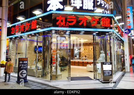 Der Karaoke-Laden mit Glasfront, Karaoke Ken in der Einkaufspassage in Dotonbori in Osaka, Japan. Blick von außen nach innen. Nacht. Stockfoto