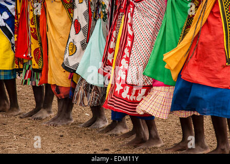 Eine Reihe von barfuß Massai-Frauen tragen die traditionelle Schals genannt Kangas, in einem Dorf in der Nähe der Masai Mara, Ostafrika Stockfoto