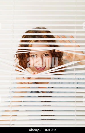 Frau, die durch Fenster blind Stockfoto