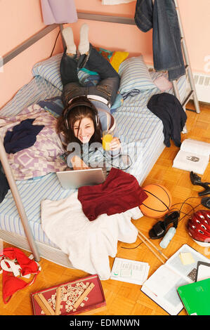 Teenager in ihrem unordentlichen Zimmer entspannend Stockfoto