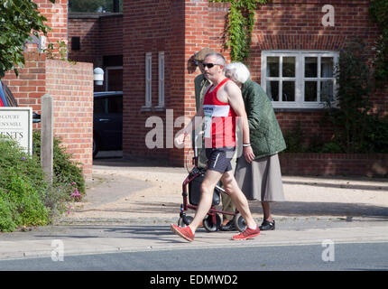 Zwei ältere Menschen, an einem Sonntagmorgen und Läufer gehen an den Start von einem Straßenrennen Stockfoto
