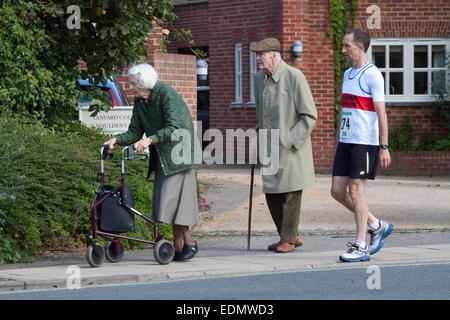 Zwei ältere Menschen, an einem Sonntagmorgen und Läufer gehen an den Start von einem Straßenrennen Stockfoto