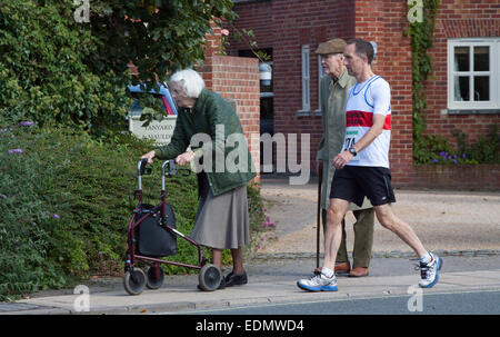Zwei ältere Menschen, an einem Sonntagmorgen und Läufer gehen an den Start von einem Straßenrennen Stockfoto
