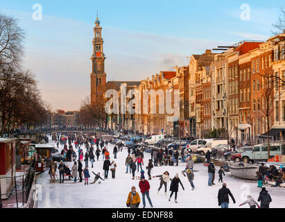 Amsterdam Eislaufen am zugefrorenen Kanal im Winter. Prinsengracht Kanal mit Westertoren Turm und Westerkerk Stockfoto