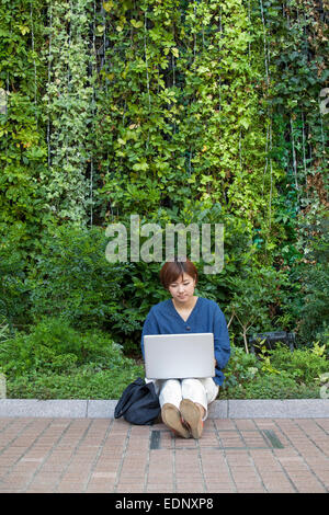 Eine Frau mit einem Laptop im Freien sitzen. Stockfoto