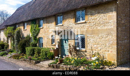 Idyllischen reetgedeckten Häuschen mit traditionellen thatching und hellen Bleiglasfenster am Taynton in Cotswolds, Oxfordshire, Vereinigtes Königreich Stockfoto