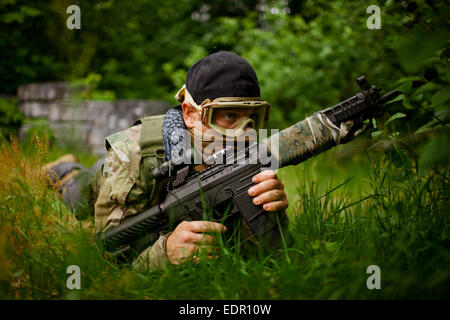 Ein Soldat hält eine Pistole während versteckt in dichten Rasen. Stockfoto