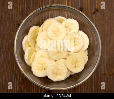 Bananenscheiben auf Schüssel auf Holztisch von oben gesehen Stockfoto