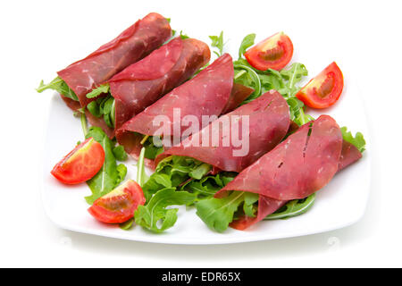 Rollen von Bündnerfleisch auf Platte auf weißem Hintergrund Stockfoto