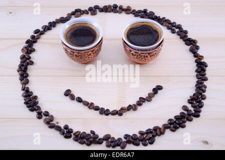 Smiley aus Kaffeekörner und zwei Vintage Tassen Kaffee als Augen gemacht Stockfoto