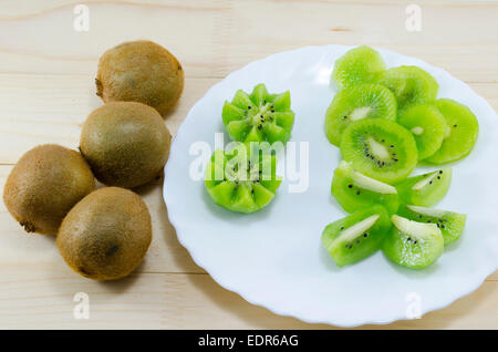 In Scheiben geschnitten und ganze Kiwi auf einem Tisch und einem Tisch Stockfoto