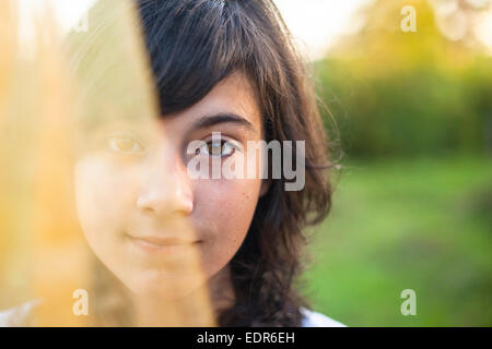 Porträt eines jungen Mädchens, die Hälfte des Gesichts ist durch durchscheinende Schleier bedeckt. Stockfoto