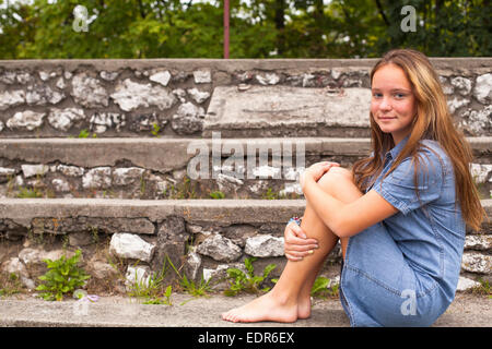 Niedlichen Mädchen sitzen auf den steinernen Stufen in den historischen Park. Stockfoto