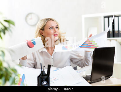 Geschäftsfrau unter riesige Unordnung auf Tisch und fliegenden Papiere Stockfoto