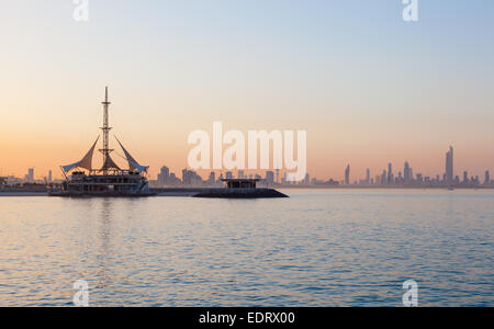 Skyline von Kuwait und Marina Wellen Pavillon bei Sonnenuntergang Stockfoto