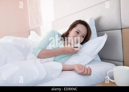 Junge Frau im Bett Sprachnachricht senden Stockfoto