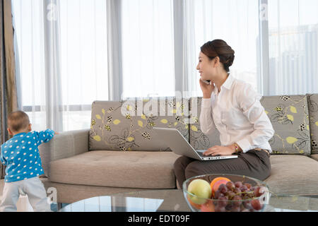 Junge Mutter mit Baby zu Hause arbeiten Stockfoto