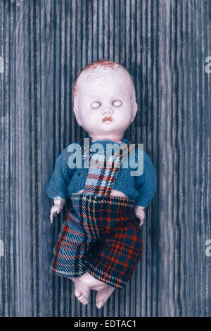 eine kaputte Puppe auf einem Holzfußboden Stockfoto