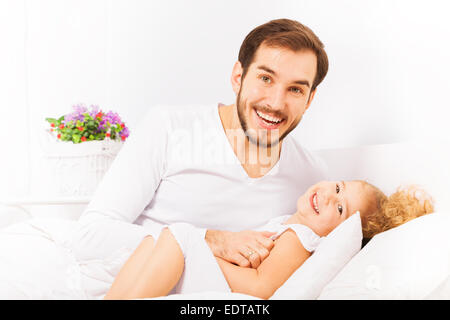 Vater umarmt, niedliche Tochter und auf Bett Stockfoto