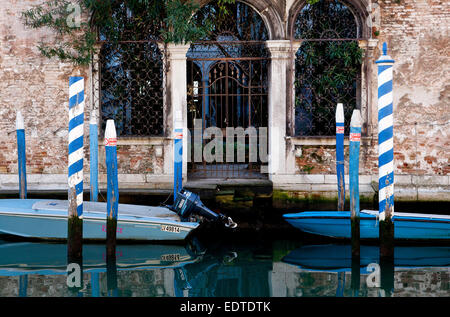 Boot vor Anker, blau + weiß Beiträge auf einem Kanal in Venedig Stockfoto