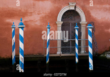 Ein Detail der blaue + weiße Liegeplatz Beiträge und Tor durch einen kleinen Kanal in Venedig Italien. Stockfoto
