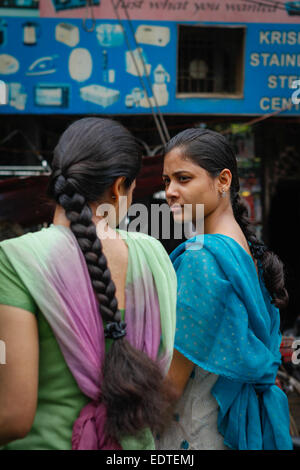 Mädchen, die während eines Verkehrsstaus ein Gespräch führen, während sie in Varanasi, Uttar Pradesh, Indien, Fahrrad fahren