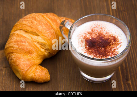 Cappuccino und Croissant gesehen auf "schließen" über Holztisch Stockfoto