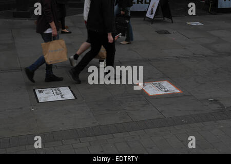 Menschen zu Fuß vorbei an Zigarettenkippen halten Sie Ihre Stadt sauber Wurf Zeichen auf Pflaster vorne Caffee Nero, Market Street, Manchester Stockfoto