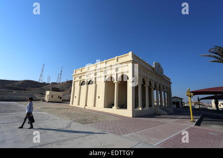 Frau zu Fuß vorbei an Bahrains Ölmuseum, mit Jebel Al-Dukhan im Hintergrund, Königreich von Bahrain Stockfoto