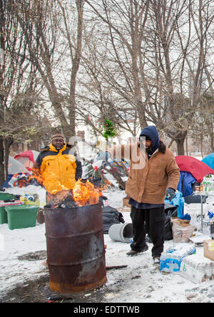 Detroit, Michigan/USA - 9. Januar 2015 - Charles (C.J.) Jones (rechts) schürt ein Feuer mit Feuerzeugbenzin in einer Zeltstadt, die Obdachlosen in der Nähe von Downtown Detroit etabliert haben. Etwa 2,5 Prozent der Einwohner von Detroit sind obdachlos, wie auch Tausende von Häusern in der Stadt leer stehen. Bildnachweis: Jim West/Alamy Live-Nachrichten Stockfoto