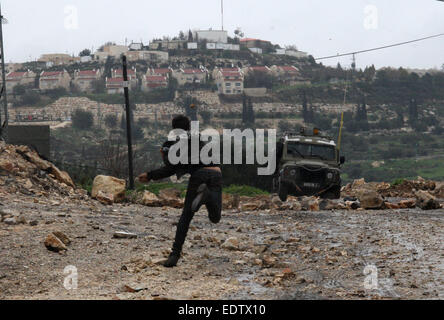 Nablus. 9. Januar 2015. Ein palästinensischer Demonstrant wirft Steinen auf israelische Soldaten bei einem Protest gegen den Ausbau der jüdischen Siedlungen im Kufr Qadoom Dorf in der Nähe von West Bank Stadt von Nablus, am 9. Januar 2015. © Nidal Eshtayeh/Xinhua/Alamy Live-Nachrichten Stockfoto