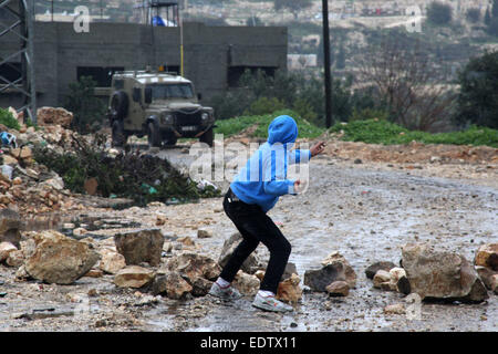 Nablus. 9. Januar 2015. Ein palästinensischer Demonstrant wirft Steinen auf israelische Soldaten bei einem Protest gegen den Ausbau der jüdischen Siedlungen im Kufr Qadoom Dorf in der Nähe von West Bank Stadt von Nablus, am 9. Januar 2015. © Nidal Eshtayeh/Xinhua/Alamy Live-Nachrichten Stockfoto